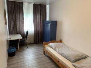 a bedroom with a bed and a desk and a window at City Hotel Dinslaken in Dinslaken