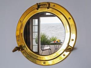 a large gold mirror with a table in front of a window at Seashore Apartment in Sandgate