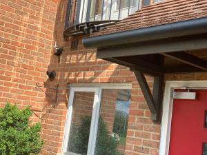 a brick building with a red door and a balcony at Private Rooms In A Cheerful 4-Bedroom Town House in Broughton