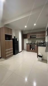 a large kitchen with a black refrigerator and wooden cabinets at Mi casa es tu casa ! in Santa Cruz de la Sierra