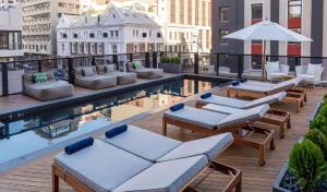 un hotel en la azotea con una piscina con tumbonas y mesas en Stay In Luxury at Stonehill Place, en Ciudad del Cabo