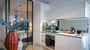 a kitchen with white cabinets and a vase at Luxury Apartment at Ellipse Waterfall, Midrand Near Mall of Africa in Midrand