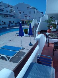 a patio with chairs and umbrellas and a pool at Blue Island House on the hill in Los Cristianos