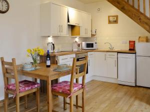a kitchen with white cabinets and a wooden table with chairs at Besss Cottage in Middlewich