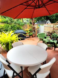 西棕櫚灘的住宿－Palm Beach Mermaid，红色伞下的白色桌子和椅子