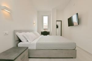 ein weißes Schlafzimmer mit einem Bett und einem Fenster in der Unterkunft Milleventi Apartments Bologna in Bologna + 20 Fotos