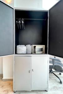 um armário branco com uma televisão e uma cadeira em La Vista EcoHouse em Macanal