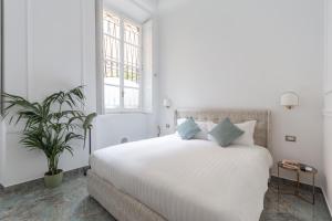 una camera bianca con letto bianco e cuscini blu di Duomo Smart Suites a Milano