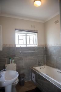 uma casa de banho com uma banheira, um WC e um lavatório. em Haithoms Guesthouse em Gaborone