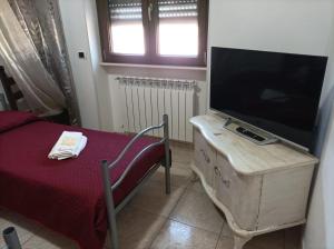 a living room with a tv and a table with a bed at B&B CASA NISI in Villa Castelli