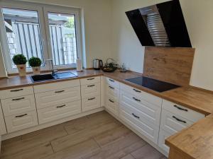 cocina con armarios blancos, fregadero y 2 ventanas en Apartment nahe Meyer Werft in Ostfriesland mit Küche & Netflix, en Westoverledingen