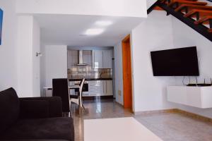 a living room with a couch and a tv on a wall at Bungalow Guayana in Mogán