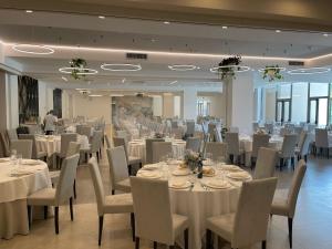 um salão de banquetes com mesas e cadeiras brancas em Hotel Ristorante Tre Lanterne & SPA em Acquasanta Terme