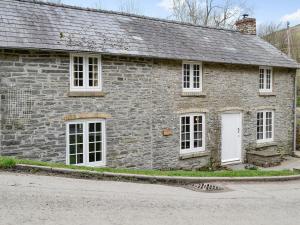 an old stone house with white windows on a street at Bridge End Cottage in Cregrina