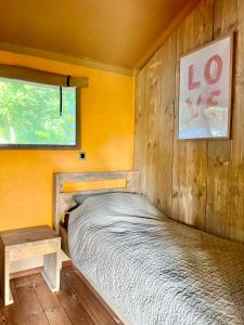 een bed in een kamer met een gele muur bij Luxe Lodgetent in Holten