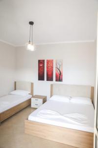 two beds in a bedroom with two paintings on the wall at Luis Penthouse in Berat