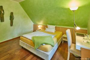 Schlafzimmer mit einem Bett mit grüner Decke in der Unterkunft Waldhotel Brand's Busch in Bielefeld