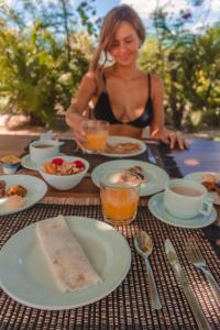 una mujer sentada en una mesa con platos de comida en Villa Praia - La Villa Group, en Jericoacoara