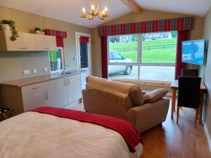 a bedroom with a couch and a kitchen with a window at Erraid Lodge in Fort Augustus