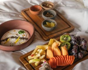 - 2 plateaux en bois avec différents types de nourriture sur un lit dans l'établissement Puerta del Cielo Hotel Origen, à Bacalar