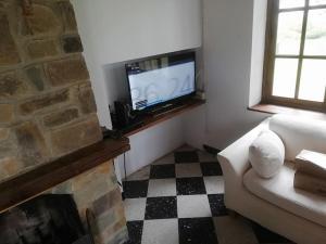 ein Wohnzimmer mit einem TV und einem Kamin in der Unterkunft Les mésanges in Rochefort