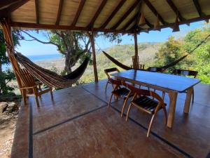 uma mesa e cadeiras num alpendre com uma rede de descanso em Stunnig Ocean View em Montezuma