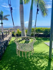 einen Schaukelstuhl vor zwei Palmen in der Unterkunft Luxury villa - best view in South Tenerife near Siam Park! in Adeje