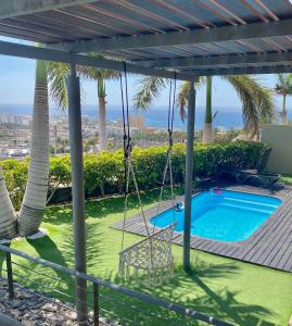 eine Veranda mit einer Schaukel und einem Pool in der Unterkunft Luxury villa - best view in South Tenerife near Siam Park! in Adeje