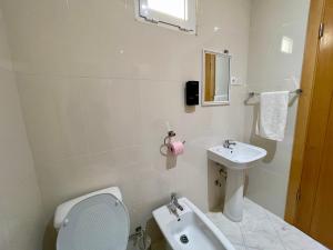 a white bathroom with a toilet and a sink at Cruzeiro Guest House in São Filipe