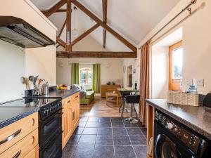 a kitchen with black appliances and a living room at The Dairy - Uk10957 in Burlton