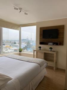 a bedroom with a bed and a large window at Departamentos Apart Hotel Chillán Center SPA in Chillán