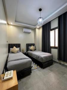 馬拉喀什的住宿－Moderne, lumineux & spacieux avec balcon -Central -Wifi-Smart TV-Clim，一间卧室设有两张床、一张桌子和窗户。