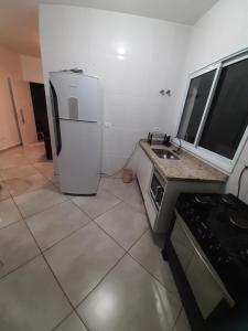 eine Küche mit einem weißen Kühlschrank und einer Spüle in der Unterkunft Sobrado frente ao SESC, WIFI 300MB, 2 vagas auto, cozinha, churrasqueira, moderno e reformado in Bertioga