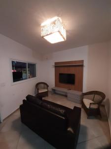 ein Wohnzimmer mit einem Sofa und einem Flachbild-TV in der Unterkunft Sobrado frente ao SESC, WIFI 300MB, 2 vagas auto, cozinha, churrasqueira, moderno e reformado in Bertioga