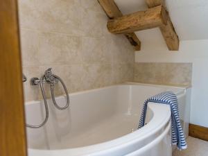 een badkamer met een wit bad en houten plafonds bij Norwood Dairy in Bredgar