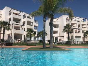 - une piscine en face d'un bâtiment avec des palmiers dans l'établissement Casa Siska, à Torre-Pacheco