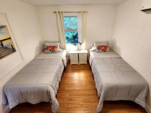 two beds in a room with a window at Mermaid's Lighthouse in West Palm Beach