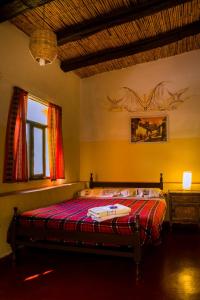 um quarto com uma cama com um edredão vermelho em Hostel Waira em Tilcara