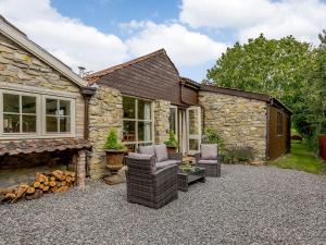 a stone house with chairs and a fireplace at Orchard Barn in Meare