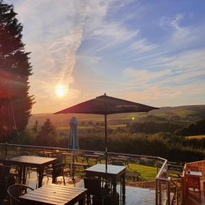 a patio with tables and an umbrella in the sunset at The Moorcock Inn in Littleborough