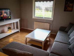 sala de estar con sofá, mesa y TV en Ferienhaus Vikeberg in Mittelschweden am Meer, en Hållnäs