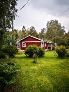 un granero rojo en un campo junto a un patio en Ferienhaus Vikeberg in Mittelschweden am Meer, en Hållnäs