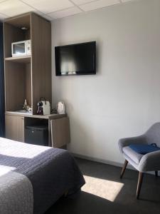 Habitación de hotel con cama, silla y TV en Résidence Cosyade équipée d'un parking privé gratuit, en Bourbourg