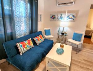 uma sala de estar com um sofá azul e duas cadeiras em Mermaid's Lighthouse em West Palm Beach