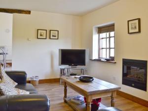 a living room with a couch and a tv and a table at Chestnut Cottage in Ebberston