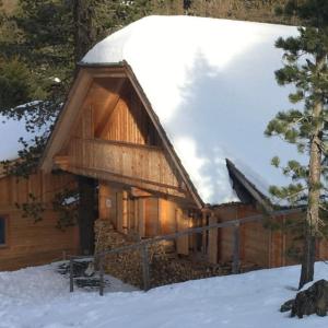 a log cabin with a snow covered roof in the snow at Turrach Chalet Haus Dachs in Ebene Reichenau