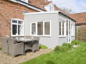 un pequeño cobertizo blanco con una mesa y sillas en un patio en Apple Tree Cottage, en Foulsham