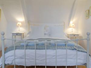 a bedroom with a white bed with two lamps at Apple Tree Cottage in Foulsham