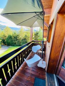 een veranda met twee witte stoelen en een parasol bij Appartement face Mont Blanc in Demi-Quartier