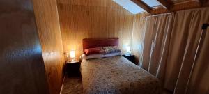 a small bedroom with a bed with two lights on it at Cabañas camelia2 in Puerto del Yate